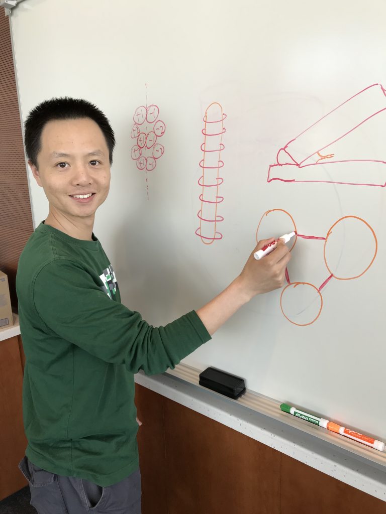 Dr. Zhao Zhang drawing diagrams of DNA-origami  structures on the whiteboard. 