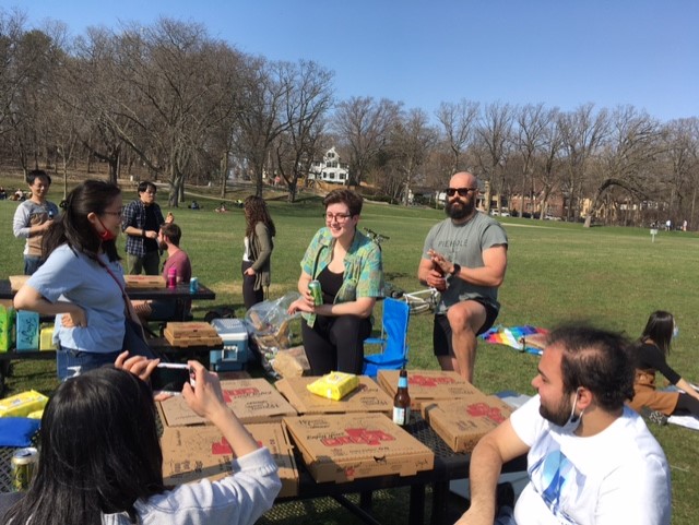 Lab members chatting in the park around pizza.